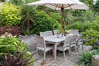 A sheltered dining terrace, separated from the lawn by raised beds of cordyline, crinum lily, lysimachia, choisya, sumach and crocosmias.