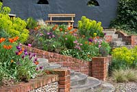Rear seating area terraced into the bank, the beds planted with Mediterranean spurge, bronze fennel and lily flowered tulips 'China Pink', 'Ballerina' and 'Burgundy'.