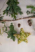 Close up detail of natural material Christmas decorations - branch decorated with stars and foliage