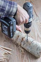 Close up detail of using a cordless drill to make candle holes in Birch wood