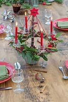 Red themed advent candle holder with lit candles as centrepiece in a table setting