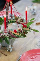 Red themed advent candle holder with lit candles as centrepiece in a table setting