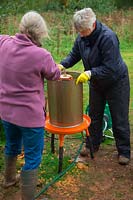 Hydropress pressing system that uses mains water pressure to extract high levels of juice from milled apples and pears in use at Community apple juicing day in Sampford Peverell, Devon, late October - assembling the mill