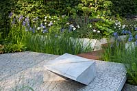 A modern garden with concrete plinth seat and Irises. RHS Chelsea Flower Show 2014. Design Hugo Bugg. Gold medal winner