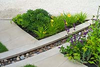 Garden detail of a rill of water and pebbles with stone paving and gravel path. Summer planting with Salvia, Hemerocallis.