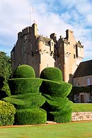 Crathes Castle Deeside Aberdeenshire with large yew topiary known as the Eggcups leading to lawns and garden