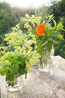 Posies of wildflowers in jars including lady's mantle, marigold, nettles and lavender.