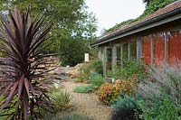 Special Plants ( Derry Watkin's garden ), Bath, UK. Late summer,  architect designed barn with informal planting around