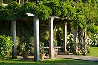 Villa La Foce, Tuscany, Italy. Large garden with topiary clipped Box hedging and views across the Tuscan countryside, the pergola with Wisteria
