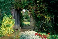 Munstead Wood Surrey Gertrude Jekyll Door in stone wall Summer garden with view of house