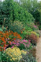 Private garden. Hampshire. Design: Barbara Hunt. Herbaceous border with Achillea 'Cerise Queen', Helenium 'Moerheim Beauty'. Fen