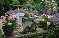 Frith Lodge Sussex Terrace patio with wicker chairs and containers Pelargonium Dolche Vita catmint and statue