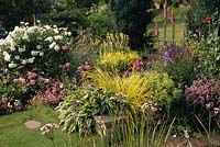 Vale End Surrey Mixed borders either side of steps in sloping garden in summer Rosa Iceberg and Constance Spry Hostas