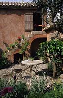 Chelsea FS 1997 Design Fiona Lawrenson Mediterranean garden with table and chairs on cobble stone patio and terra cotta colour w