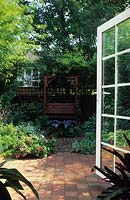 small private town garden patio Manchester Design Alan Titchmarsh covered seat in shady garden with water feature and tile floor
