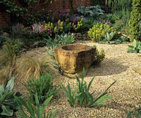 Dry Gravel garden May Thursley Lodge; Surrey. Design: Fiona Lawrenson. Dry; Gravel garden. Mortar 'sculpture'. Stipa arundinarea