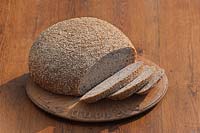six grain round sour dough local fresh loaf bread hand made edible kitchen food knife sliced slices breadboard table still life