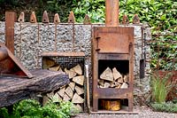 Walker's Forgotten Quarry Garden. Old rusted wood stove and logs. Designer: Graham Bodle. Sponsor: Walker's Nurseries