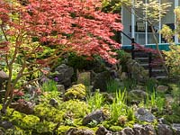 The Green Switch garden. The large shallow water feature with moss covered rocks planted with Blue Iris and surrounded by Acer Palmatum and Bonsai trees is overlooked by the garden studio.  Large green balls of Moss provide the backdrop. Design: Kazuyuki Ishihara. Sponsor: G Lion