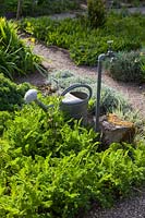 Metal watering can and outdoor tap in gravel garden. 