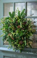 Natural Christmas wreath on a back door. Decorations include mistletoe, pine cones, box, green and blue spruce, golden sprayed gypsophila and cinnamon sticks