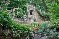 Tower above Chapels Tunnel  seen from below with Hydrangeas and Japanese Anemones. Sintra, Portugal.