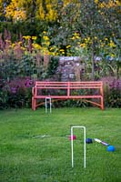 Garden bench and croquet set on garden lawn. 
