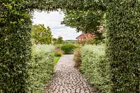 View down cobbled stone path in The Walled Garden at Bury Court Gardens, Hampshire, UK.