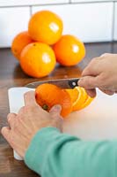 Slicing oranges on kitchen worktop