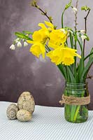 Arrangement with spring flowers and easter decorations on Gingham tablecloth.