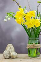 Easter arrangement with Daffodils, spring snowflake and decorated wooden Easter eggs.