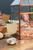 Copper themed Easter display in copper lantern with place names made from chicken shaped name cards fixed to pebble with copper wire