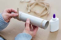 Woman adding layer of jute ribbon to glued layer to create a napkin ring