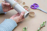 Woman removing dried jute ribbon rings from cardboard tube