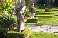 A pair of sculptures by Simon Verity, frame a gate out of the main garden. Barnsley House, Cirencester, Glos, UK. 