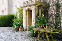 An old wooden barrow is used to display seasonal pots of flowers outside the main door of the hotel at Barnsley House, Cirencester, Glos, UK. 