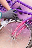 Woman spraying old childs bike with purple paint