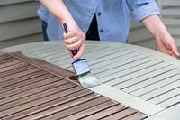 Woman painting garden furniture with paint brush