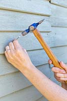 Hammering nail into wooden shed 