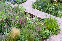 Astrantia 'Moulin Rouge' with perennials and grasses and Iris 'Silver Edge ' with ferns along brick paved path - RHS Feel Good Garden - Built by Rosebank Landscaping - Sponsor: the RHS - RHS Chelsea Flower Show 2018