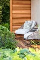 The Morgan Stanley Garden for the NSPCC - Seating area with armchairs with Euphorbia characias 'Black Pearl' - Sponsor: Morgan Stanley - Chelsea Flower Show 2018