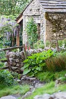 Welcome to Yorkshire Garden - Stone building over wall and fence - Sponsor: Welcome to Yorkshire - RHS Chelsea Flower Show 2018