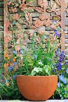 The Silent Pool Gin Garden - Pot with decorative corten steel panel on drystone wall - Corydalis flexuosa 'China Blue', Brunnera 'Alexander's Great', and Cow Parsley - Anthriscus sylvestris - Sponsor: Silent Pool Distillers - RHS Chelsea Flower Show 2018