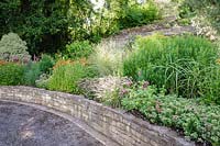 View of raised sloping bed combining ornamental grasses and herbaceous perennials.