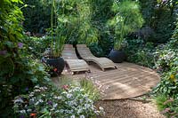 Twin wooden seats on decking with mixed planting. Pensees Jardinieres, 
Gardening Thoughts. Festival garden. Garden of Thought.  
Festival des Jardins 2018, Chaumont sur Loire, France 