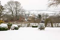 Snow-covered lawn with old water bowser with views across the white hills of the Blackmore Vale