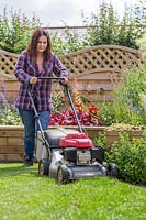 Woman cutting lawn with petrol lawn mower