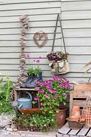 Outdoor arrangement with suitcase, boots and handbag planted up with mixed flowers and foliage plants