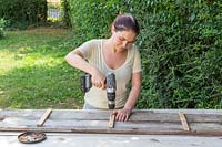 Fixing together two long boards with small cross timbers using electric screwdriver
