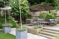 Large garden in St John's Wood - raised deck seating area with large parasol and 
 contemporary zinc containers with Betula utilis Jaquemontii 
